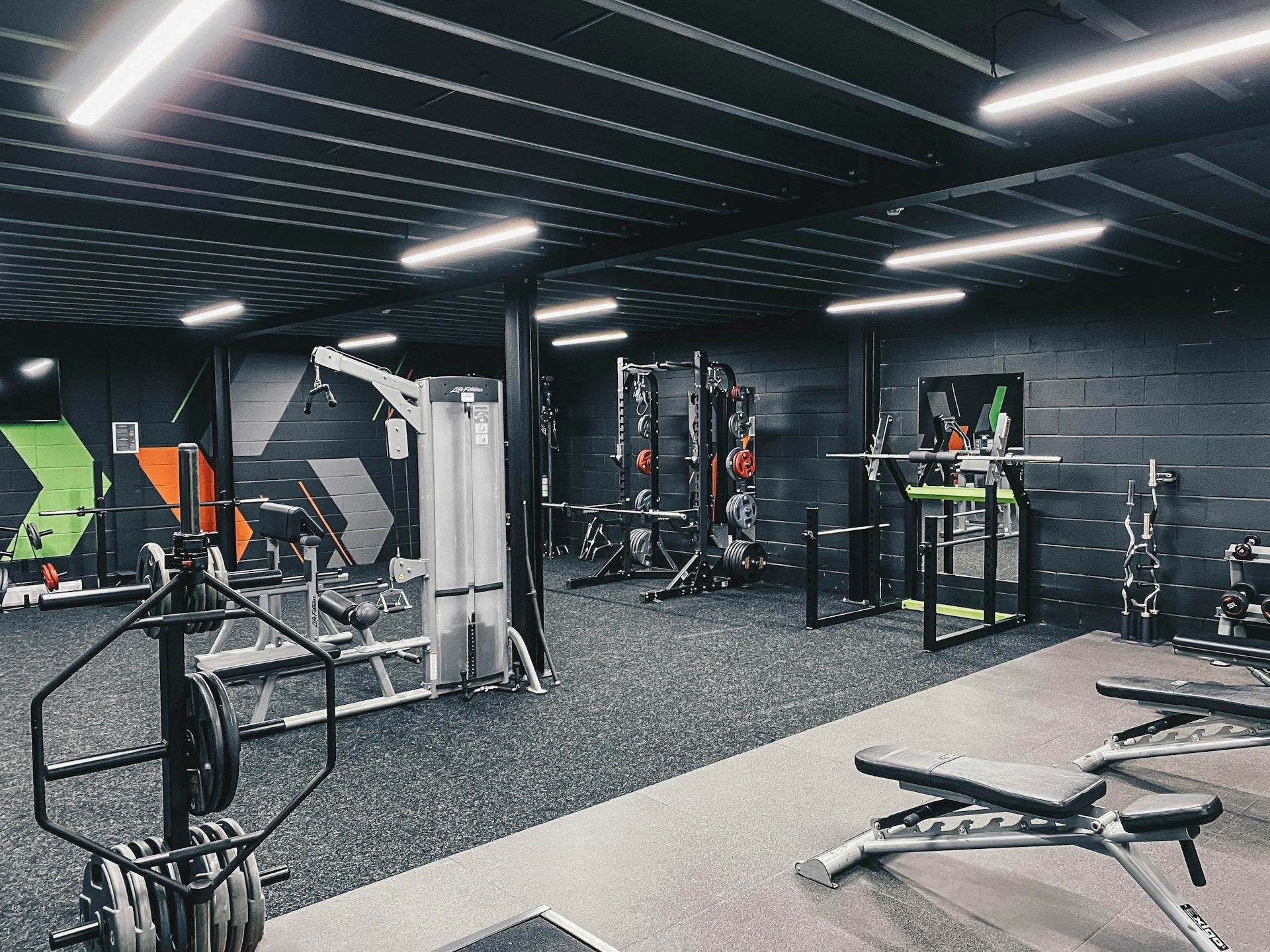 Modern gym with premium weightlifting equipment, benches, and geometric wall art accents