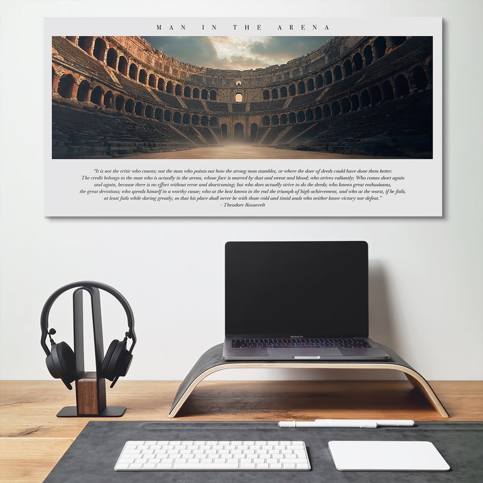 Modern desk setup with laptop and headphones beneath IKONICK Man in the Arena motivational canvas wall art.