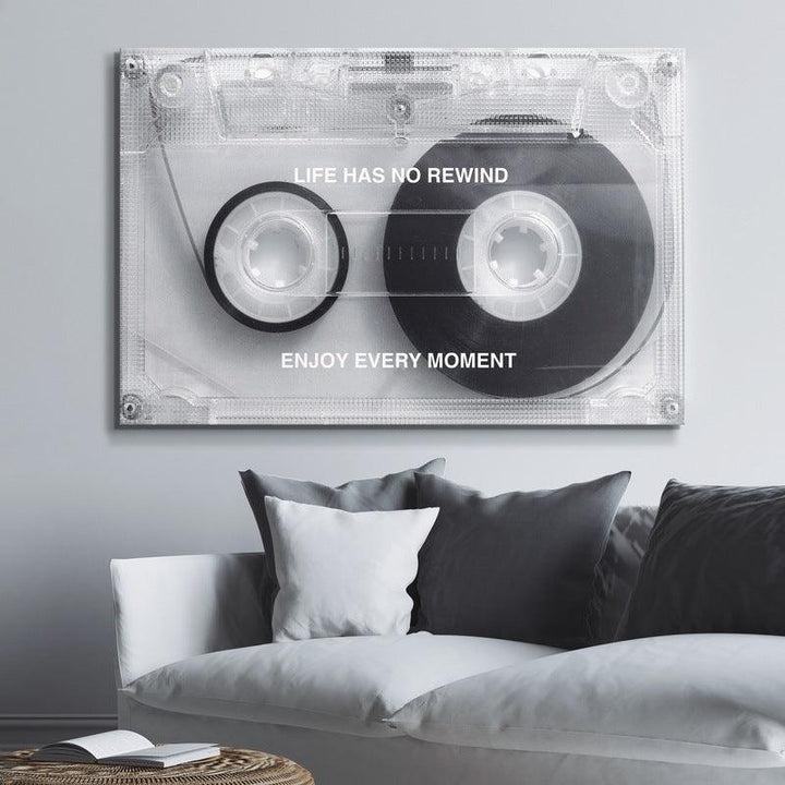 Motivational cassette tape wall art with 'Life Has No Rewind' quote above a modern sofa.